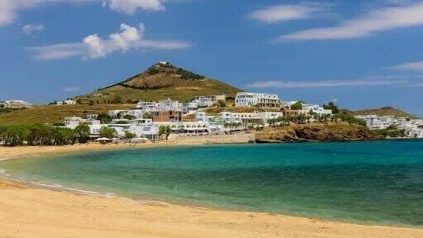 A coastal town with buildings on a hillside overlooking a sandy beach and clear blue waters. - Beachfront Bocamviglies Room - Naoussa Sunny Suite (Naoussa)