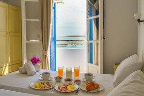 Ein ordentlich bezogenes Bett mit einem Frühstückstisch, gedeckt mit Speisen, Getränken und einer Blumenvase.