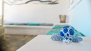 A turtle figurine on a white table in a room with a white wall and a blue and white patterned wall hanging. - Beachfront Bocamviglies Room - Naoussa Sunny Suite (Naoussa)