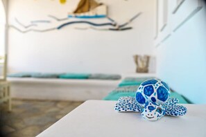 A turtle figurine on a white table in a room with a white wall and a blue and white patterned wall hanging. - Beachfront Bocamviglies Room - Naoussa Sunny Suite (Naoussa)