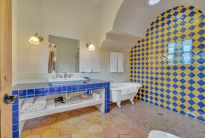Un baño con tocador azulado de azulejos, una bañera blanca y un pared con estampado azul y amarillo.