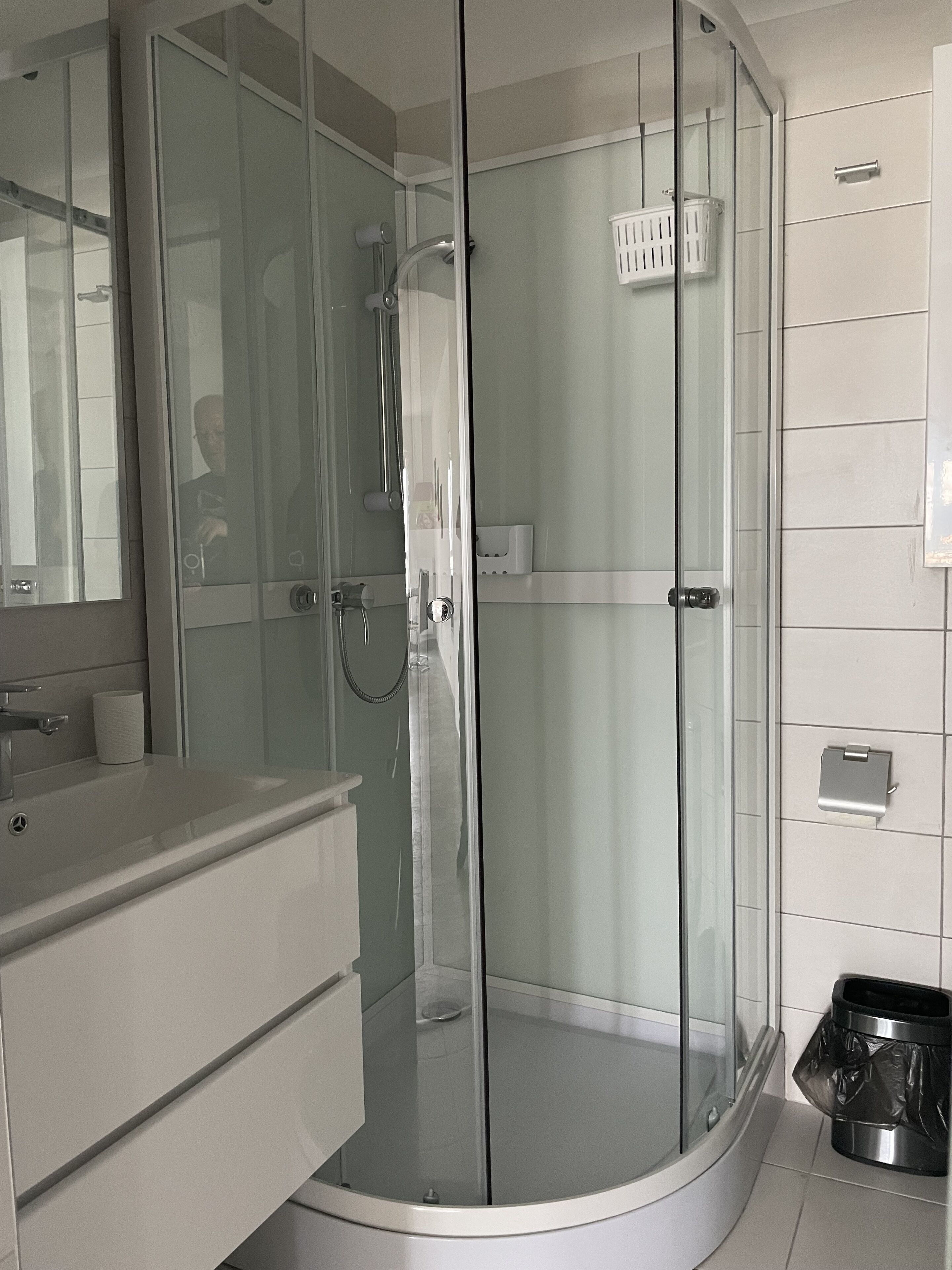 Ein modernes Badezimmer mit einer Glasdusche, einem Waschtisch mit Spiegel und einer Toilette.