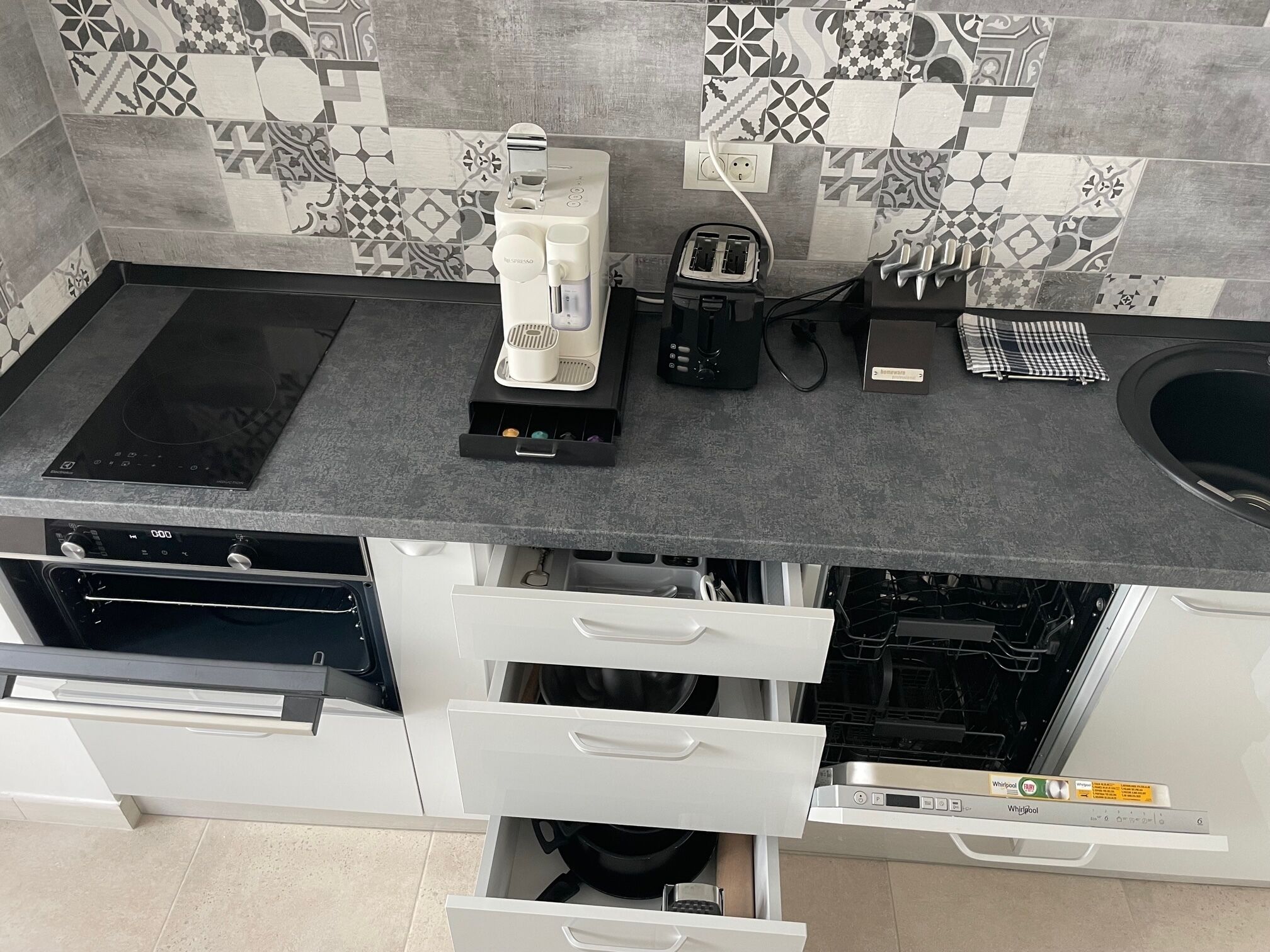 Una cocina moderna con horno integrado, cafetera, tostadora y lavavajillas.