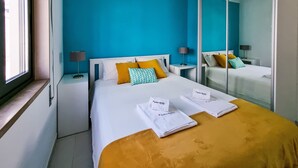 Une chambre d’hôtel avec un grand lit, deux tables de chevet, une fenêtre et un miroir.