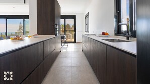 Uma cozinha moderna com armários de madeira escura, uma ilha grande e vista para o exterior.