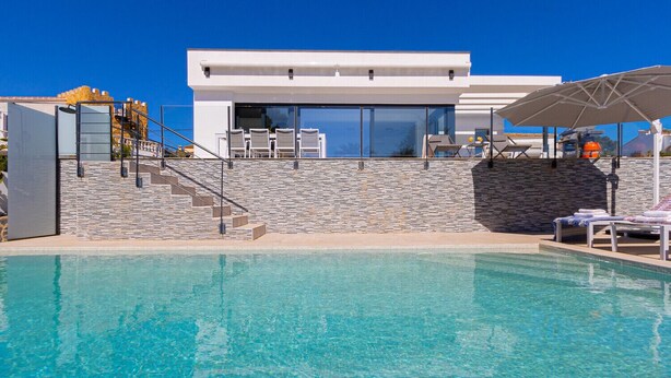 Um edifício moderno com piscina, paredes de pedra e área de estar externa.