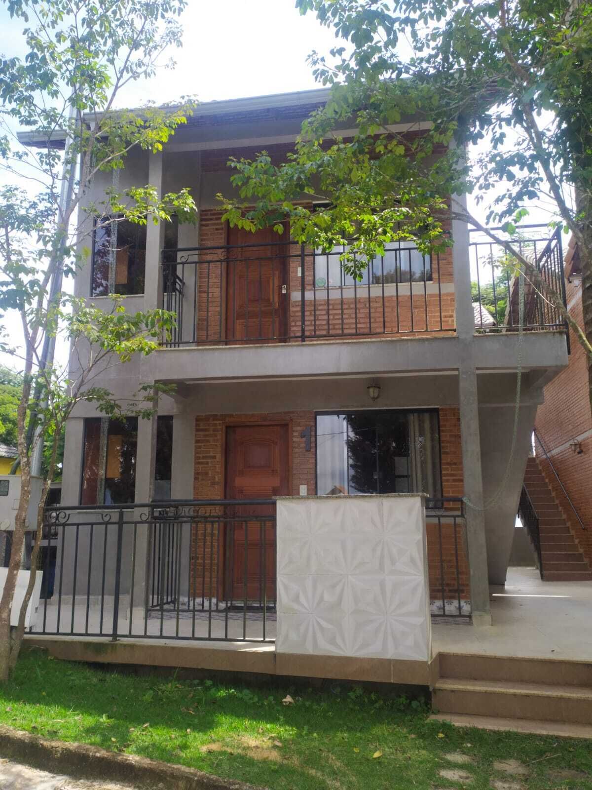 Un edificio de dos pisos con un balcón, una escalera y una entrada con portón.