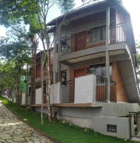 Un edificio de varios pisos con balcones, un camino de piedra y árboles.