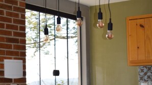 Una cocina con pared de ladrillo, ventana con vistas, bombillas colgantes y salpicadero de azulejos.
