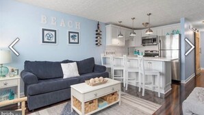 Ein modernes Wohnzimmer mit blauer Wand, grauem Sofa und weißem Couchtisch.