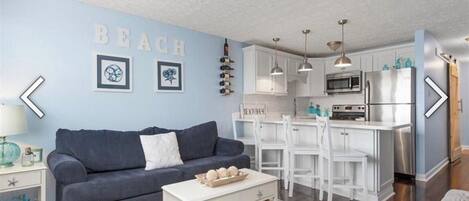 A modern living room with a blue wall, a grey sofa, and a white coffee table.