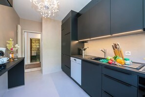 Ett modernt kök med mörka skåp, diskmaskin och en bänkskiva där färska råvaror och köksredskap står framme.