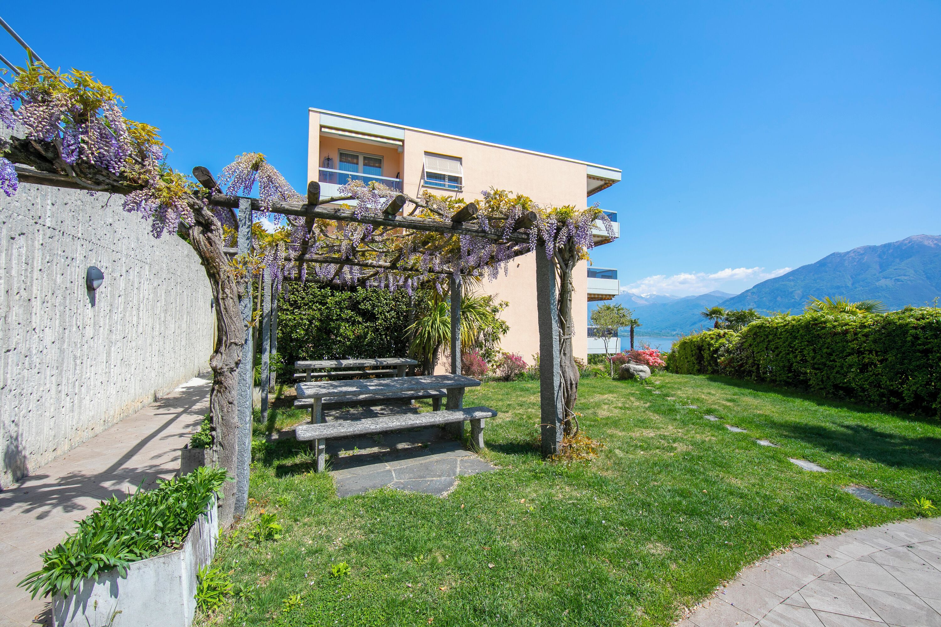 A garden with a pergola, stone steps, and a view of a mountain.