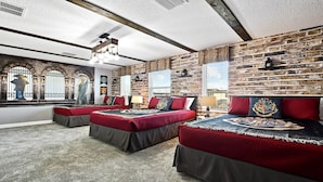 Ein Zimmer mit Ziegelwand, zwei Betten mit roter Bettwäsche, einer Chandelüster und einem großen Fenster mit Blick.