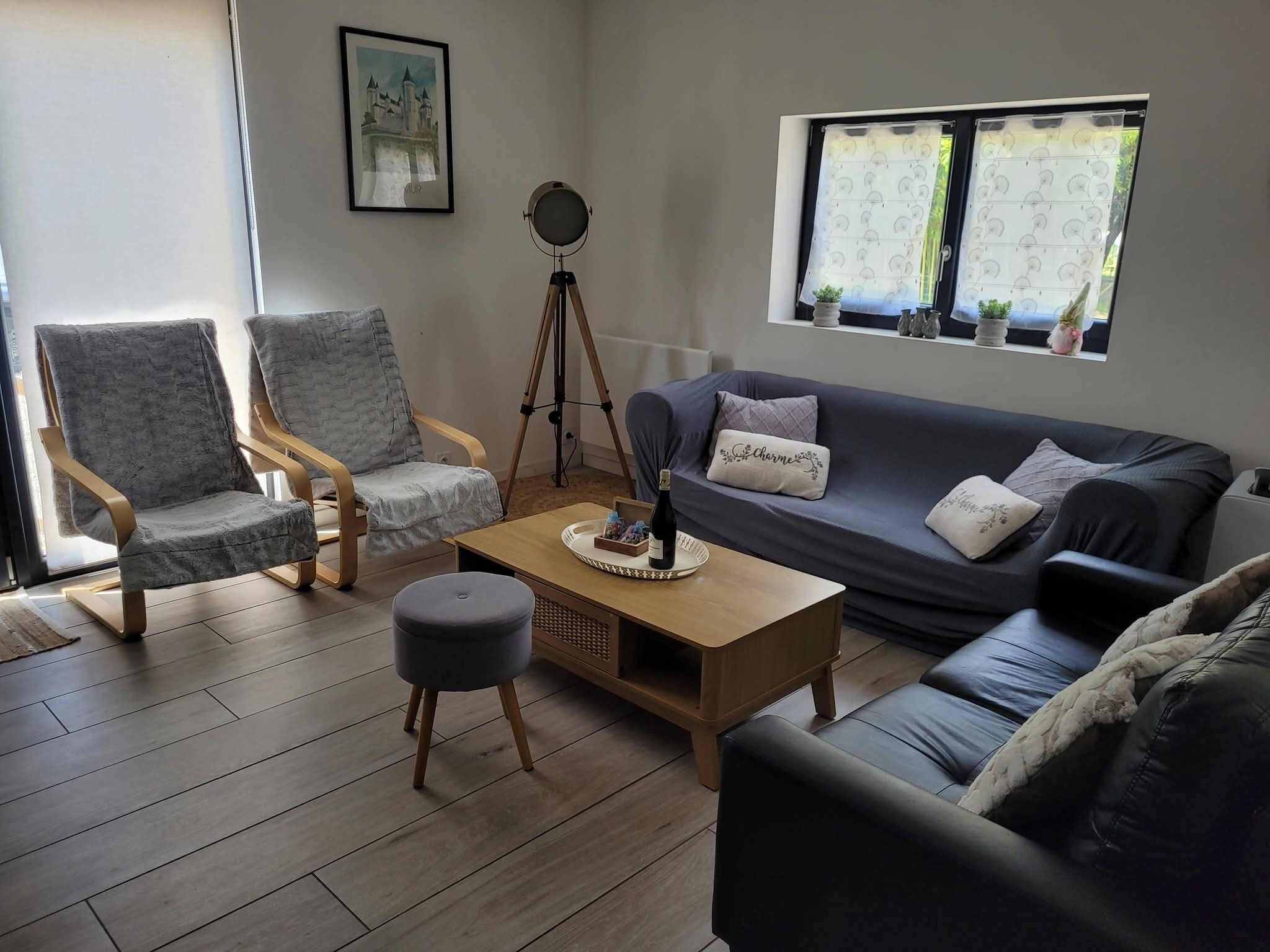 Un salon comprenant un canapé, deux fauteuils, une table basse et un trépied.