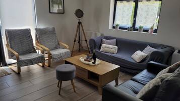 Un salon comprenant un canapé, deux fauteuils, une table basse et un trépied.