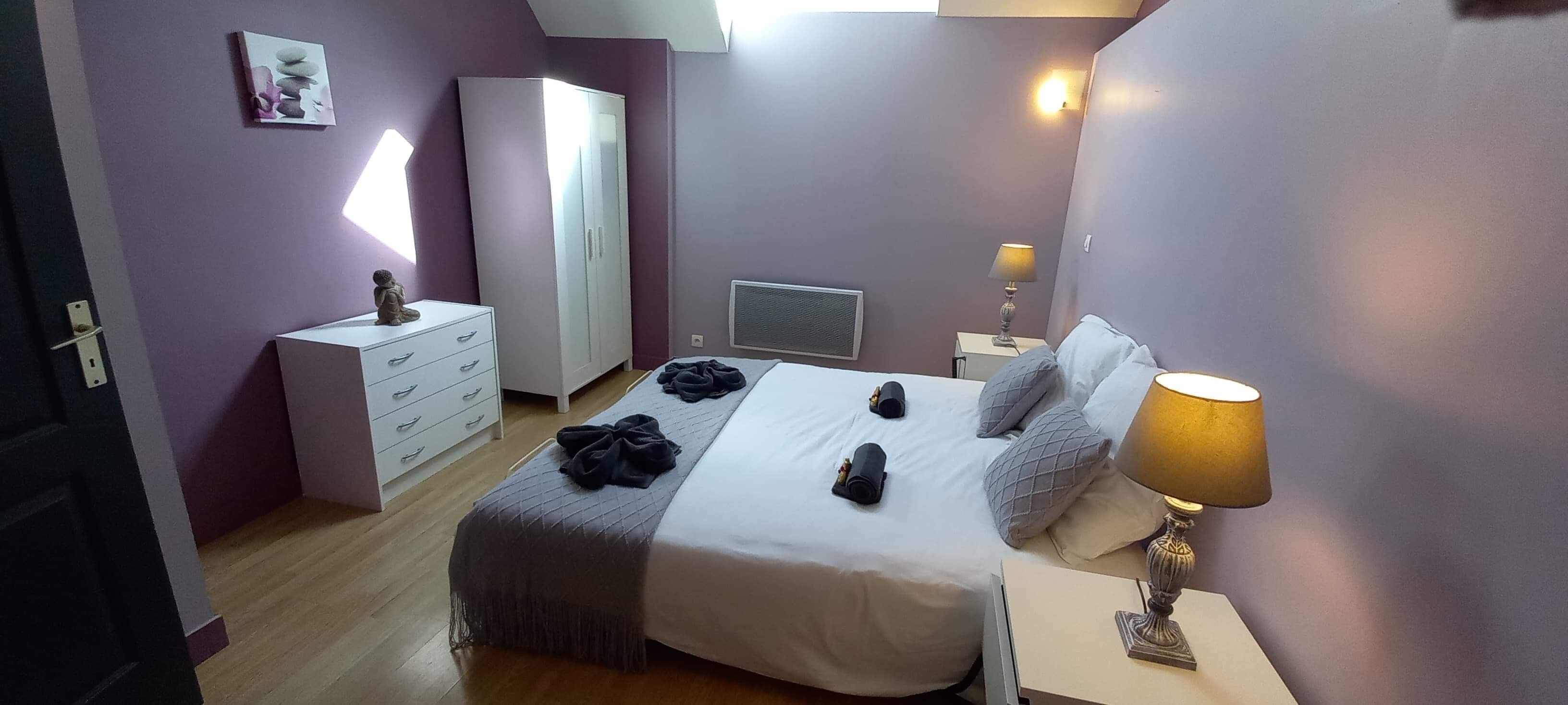 A bedroom with a bed, a wardrobe, a desk, and a lamp.