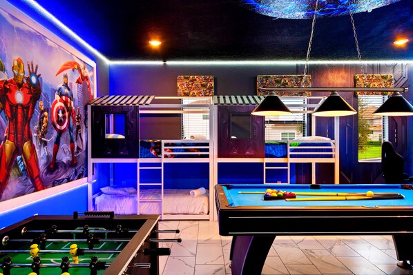 A room with a pool table, foosball table, bunk beds, and a mural of superheroes. - Last Minute Disney! Private Pool, Hot Tub, Game Room & Themed Bedrooms. Book Now! #56475 (Orlando)