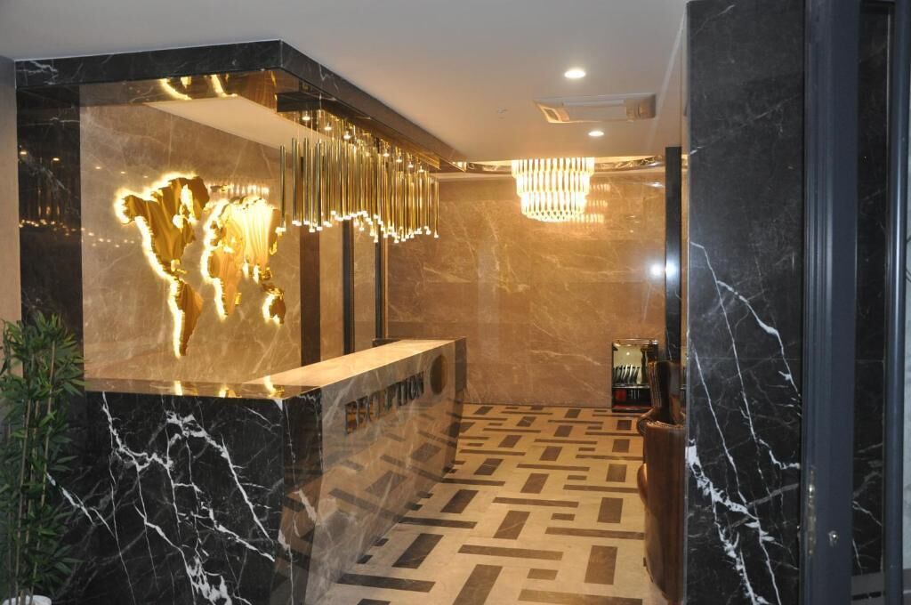 A reception area with a marble floor, a reception desk, and a modern chandelier.