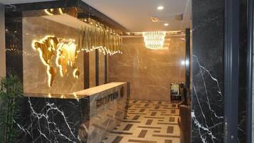 A reception area with a marble floor, a reception desk, and a modern chandelier.