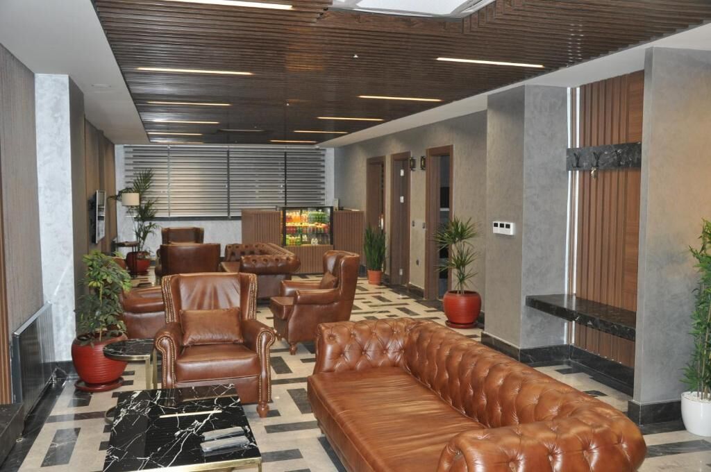 A lobby with leather sofas, a marble coffee table, and potted plants.