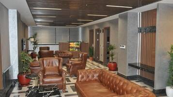 A lobby with leather sofas, a marble coffee table, and potted plants.