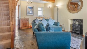 Ein Wohnzimmer mit einem blauen Sofa, einer Holztreppe, einem Kamin und einem großen Spiegel an der Wand.