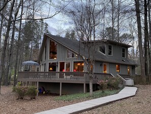 Une cabane à deux étages avec une terrasse, entourée d’arbres.