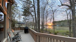 A wooden deck with outdoor seating, overlooking a lake with a sunset view. - Reduced Spring rates! On Lake Oconee with Sunset Views, 2 Masters (Eatonton)