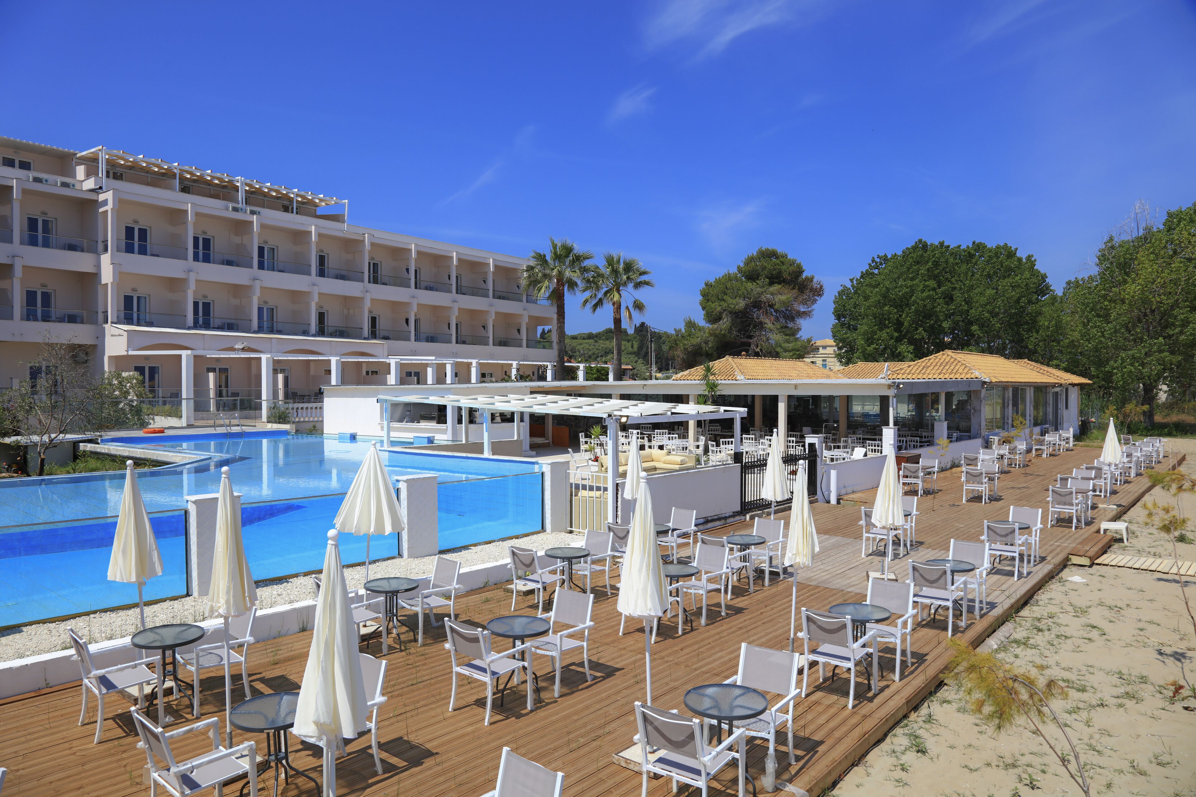 A resort with a large swimming pool, outdoor seating with umbrellas, and a building with multiple balconies.