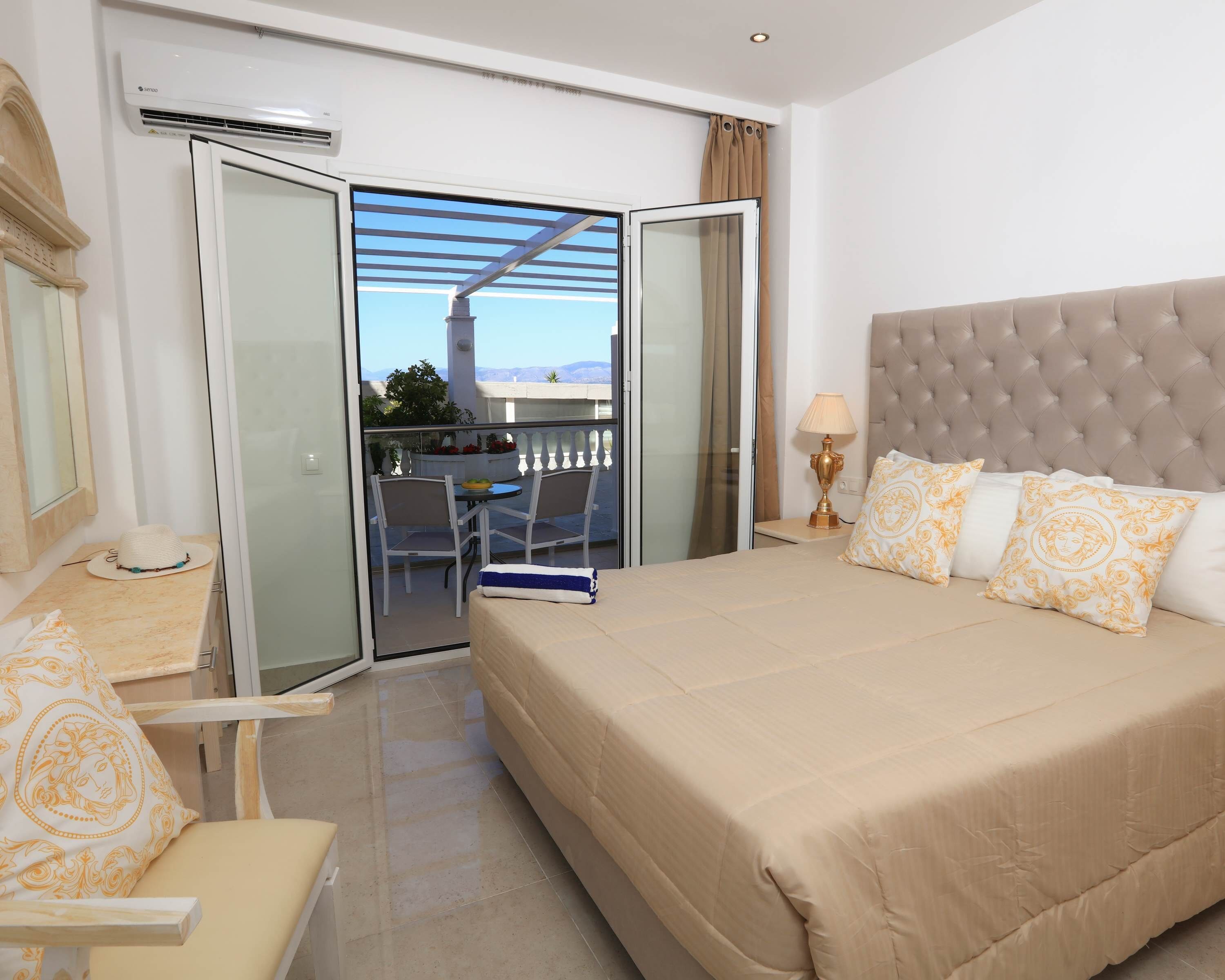 Een hotelkamer met een bed, een stoel, een tafel met een lamp en een balkon met uitzicht.