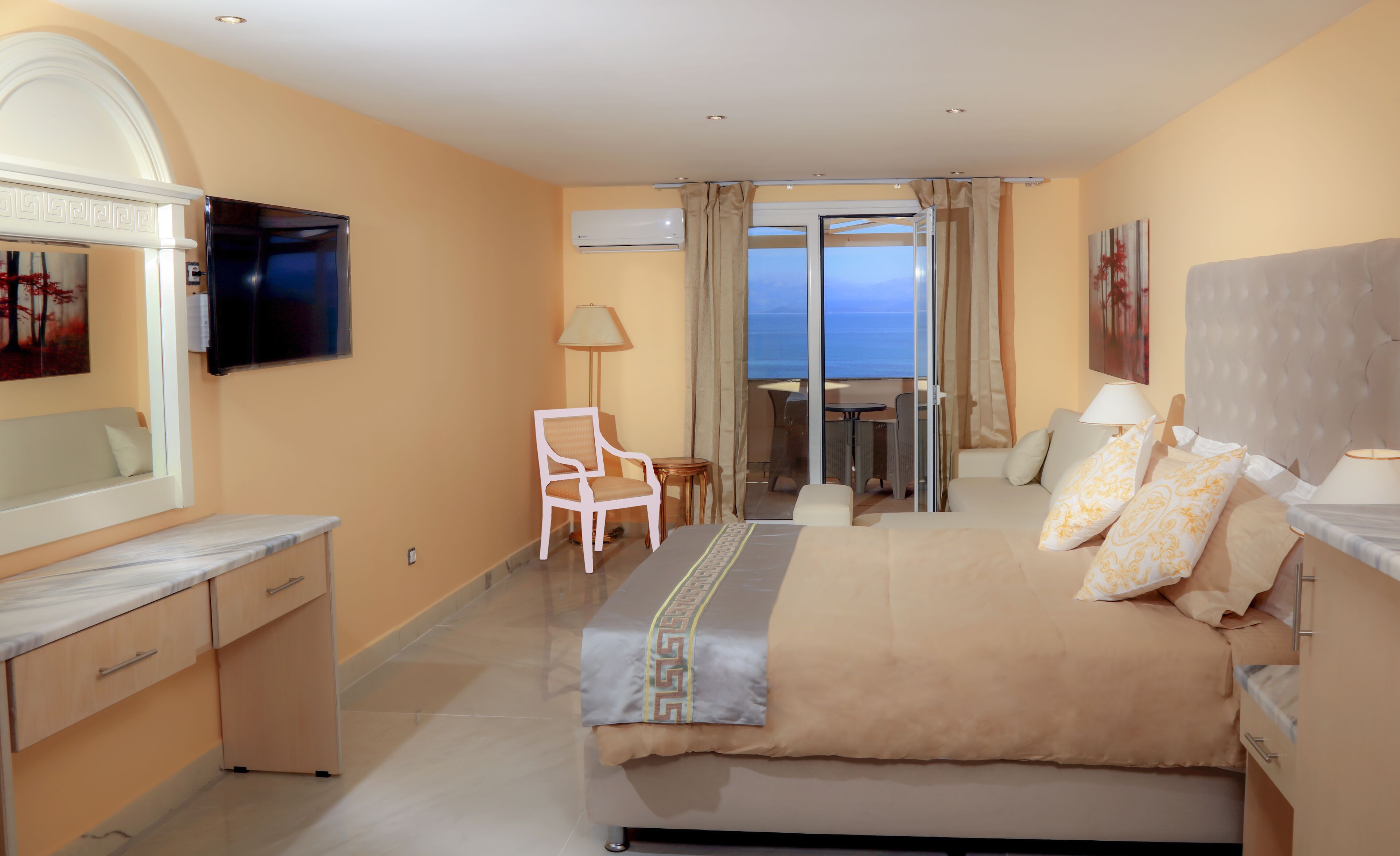Une chambre d’hôtel avec un lit, un bureau, une chaise, une télévision et une vue sur la mer.