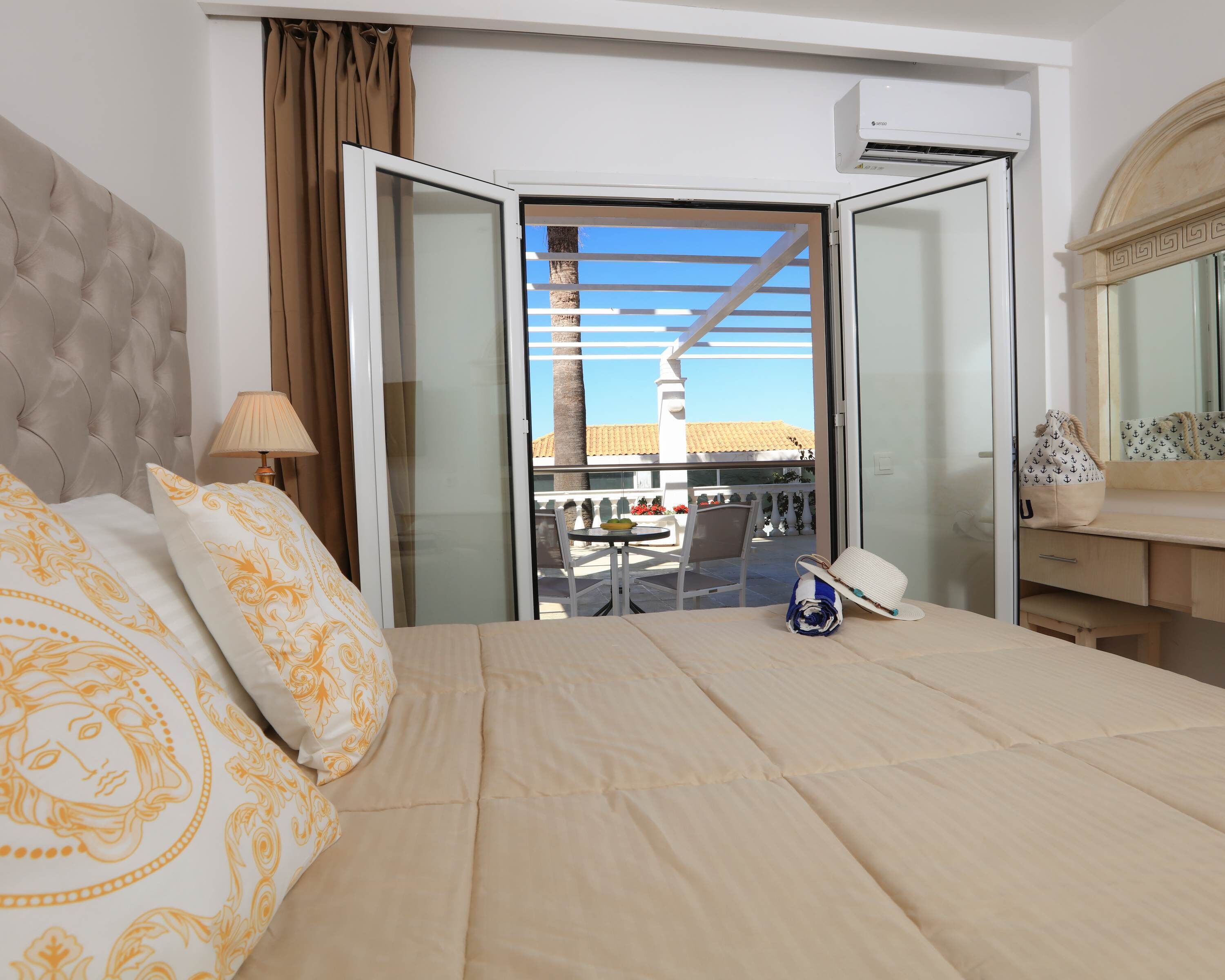 A hotel room with a bed, a lamp, a suitcase, and a view of the outside balcony.