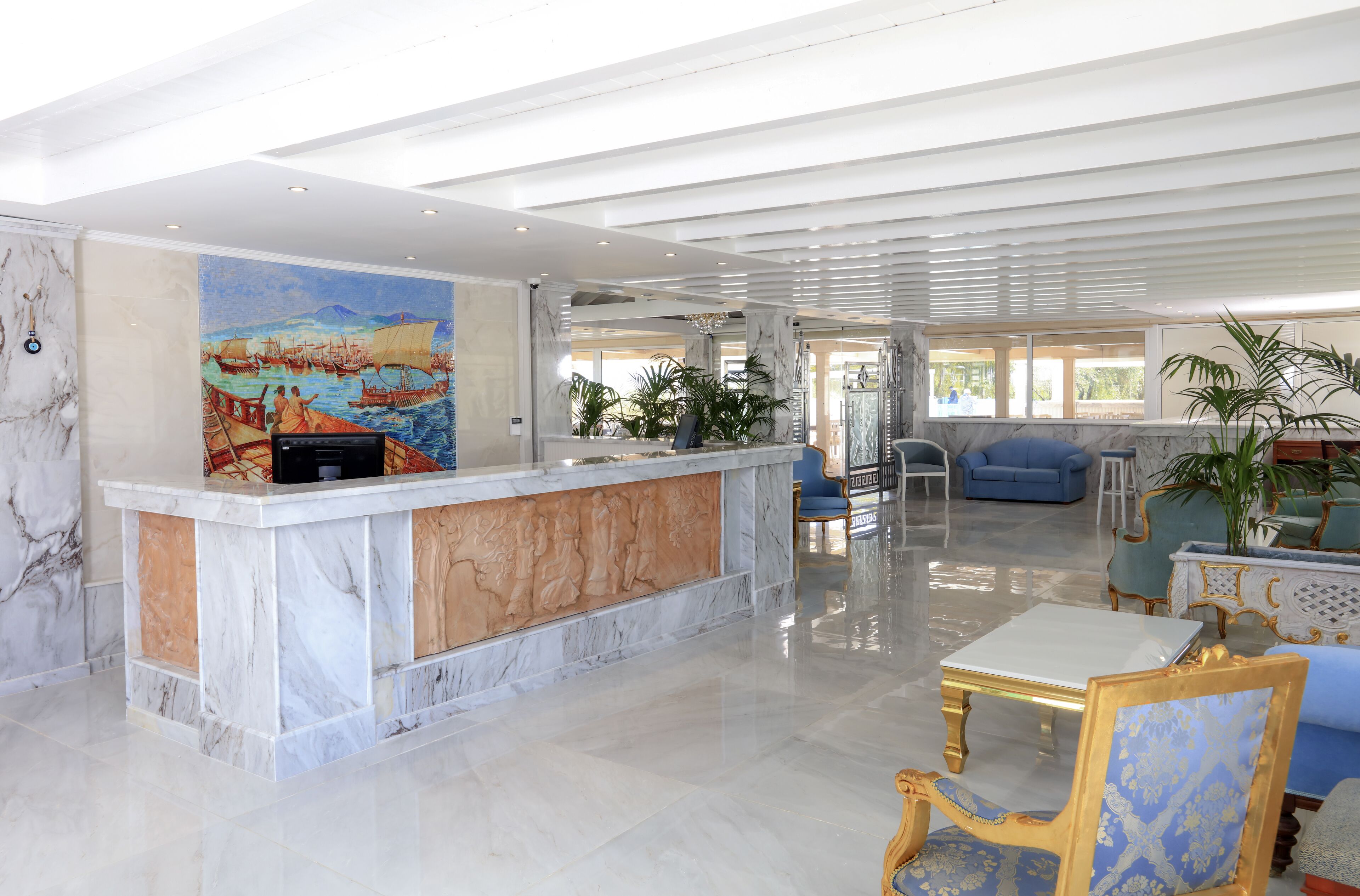 A spacious lobby with a marble reception desk, seating area, and large windows.