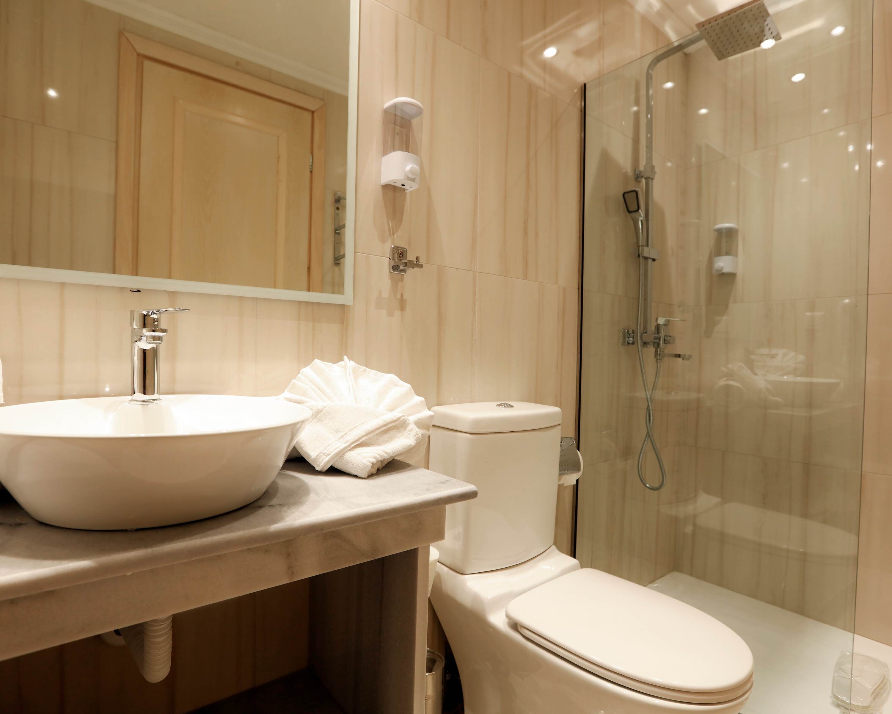 A modern bathroom with a large sink, toilet, and glass-enclosed shower.