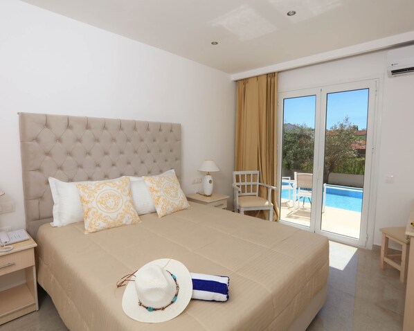 A hotel room with a large bed, a nightstand, a lamp, a chair, and a view of a swimming pool through a sliding glass door.