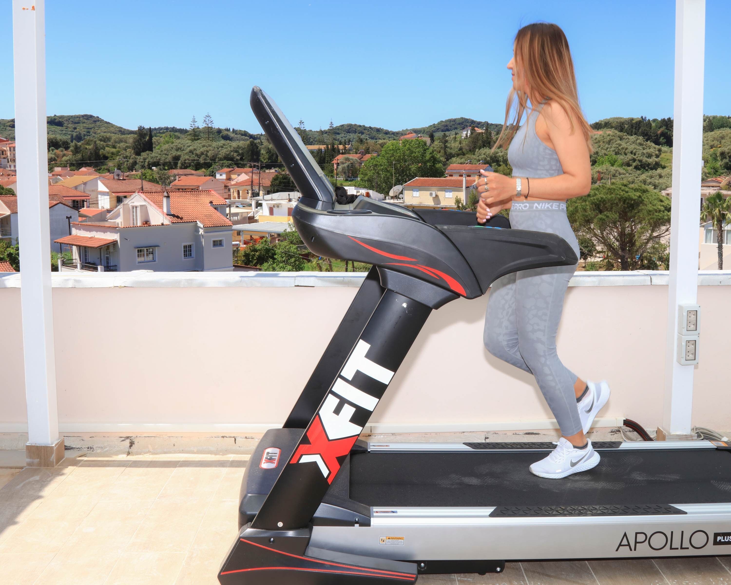 A woman running on a treadmill with a cityscape in the background.