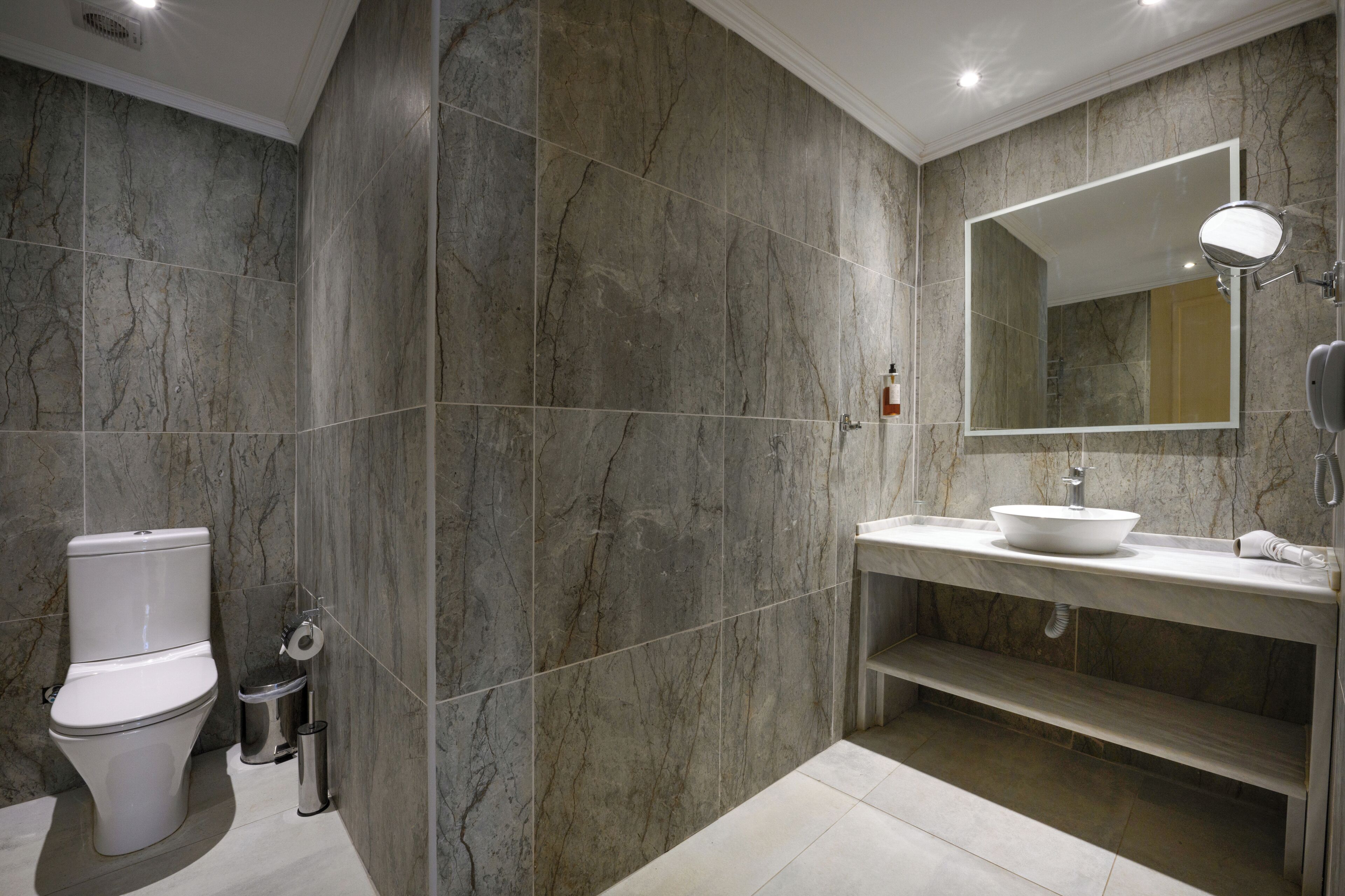 A modern bathroom with a toilet, sink, and mirror.