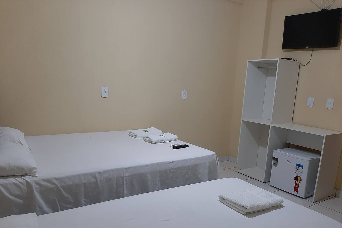 Een kamer met twee bedden, een televisie en een minibar.