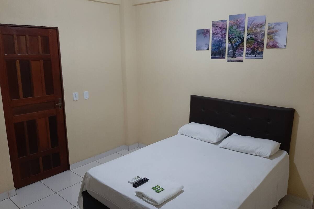 Een hotelkamer met een bed, een houten deur en drie aan de muur hangende foto's.