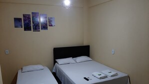 A room with two single beds, a wall-mounted light fixture, and four framed pictures. - Hotel Rio Tapajós (Santarém)