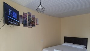 A hotel room with a bed, a TV mounted on the wall, and a ceiling light fixture. - Hotel Rio Tapajós (Santarém)