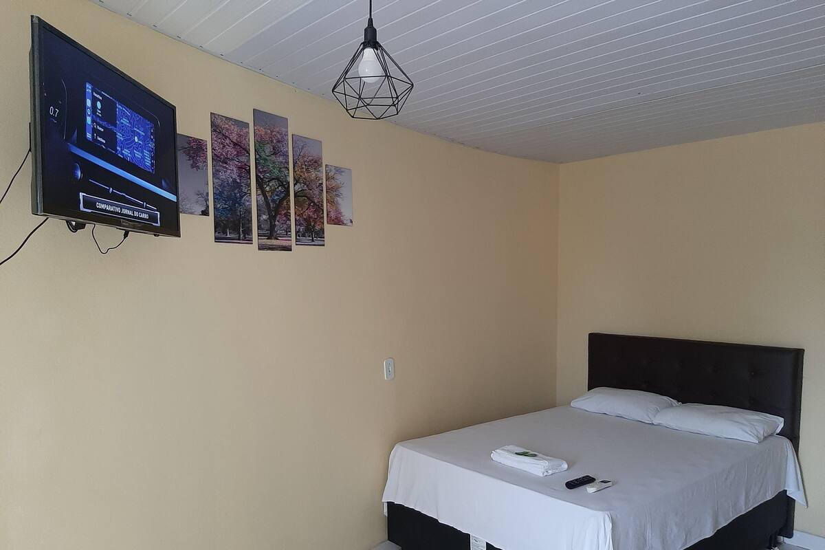 Een hotelkamer met een bed, een aan de muur bevestigde televisie en een plafondlamp.