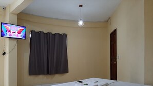 A hotel room with a bed, a television mounted on the wall, a curtain, and a ceiling light. - Hotel Rio Tapajós (Santarém)