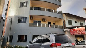 A multi-story building with balconies, a parked car, and a visible storefront with a sign. - Hotel Rio Tapajós (Santarém)