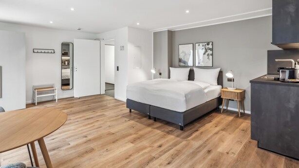 A modern hotel room with a large bed, bedside tables, a desk, and a wardrobe. - Limehome Salzgitter A.-Schweitzer-Str. (Salzgitter)