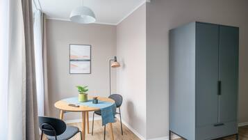 A modern room with a dining table, chairs, a cabinet, and a hanging light fixture.