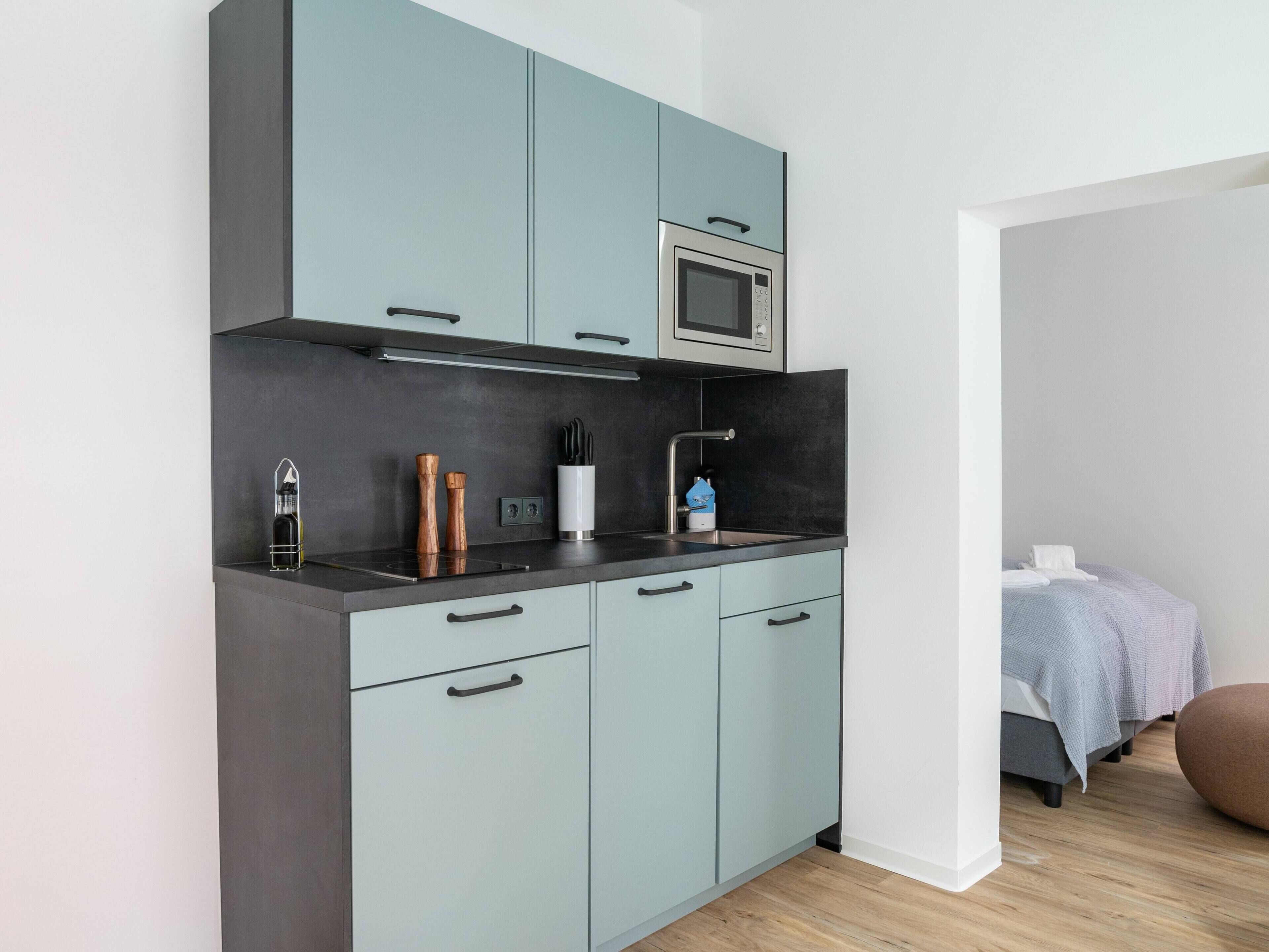 Une cuisine moderne avec des meubles gris, un four à micro-ondes et un évier.