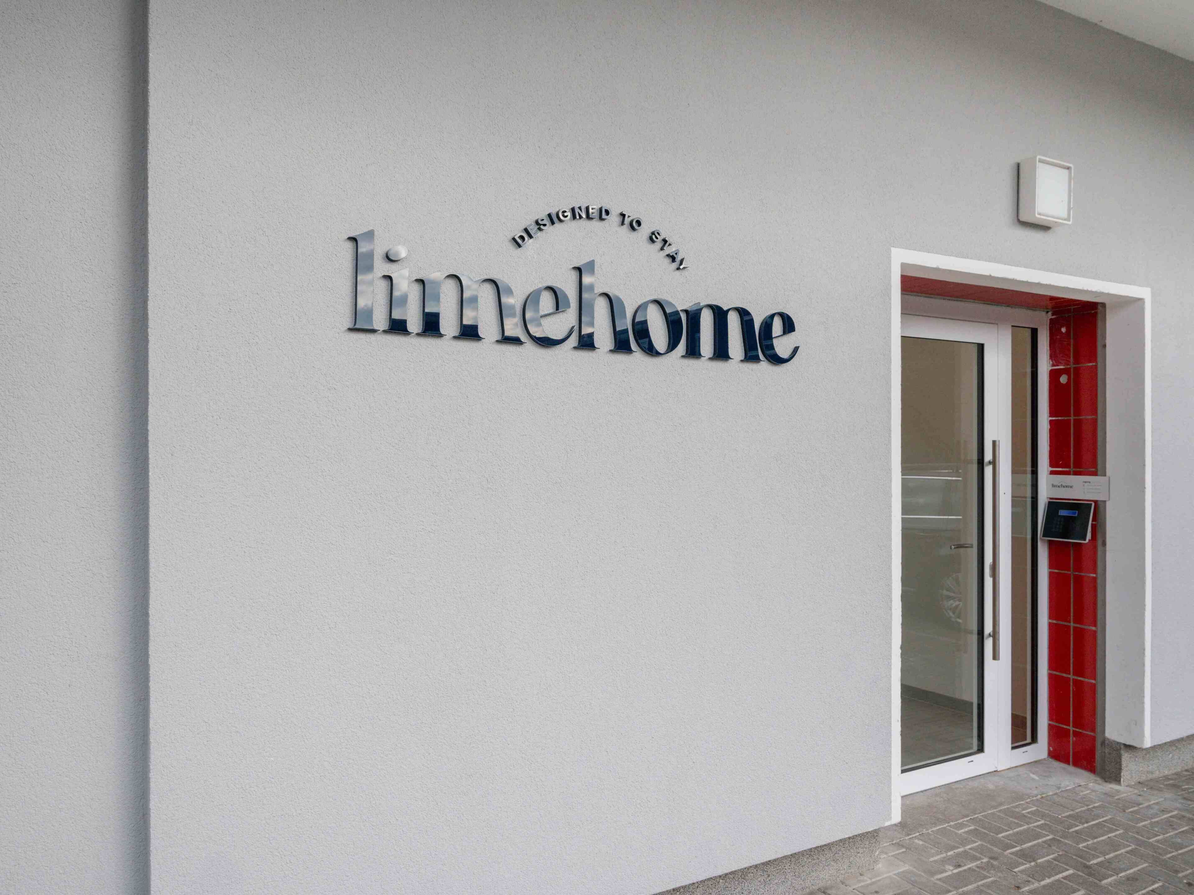 A building facade with a sign reading "limelimehome" and a door with a red frame.