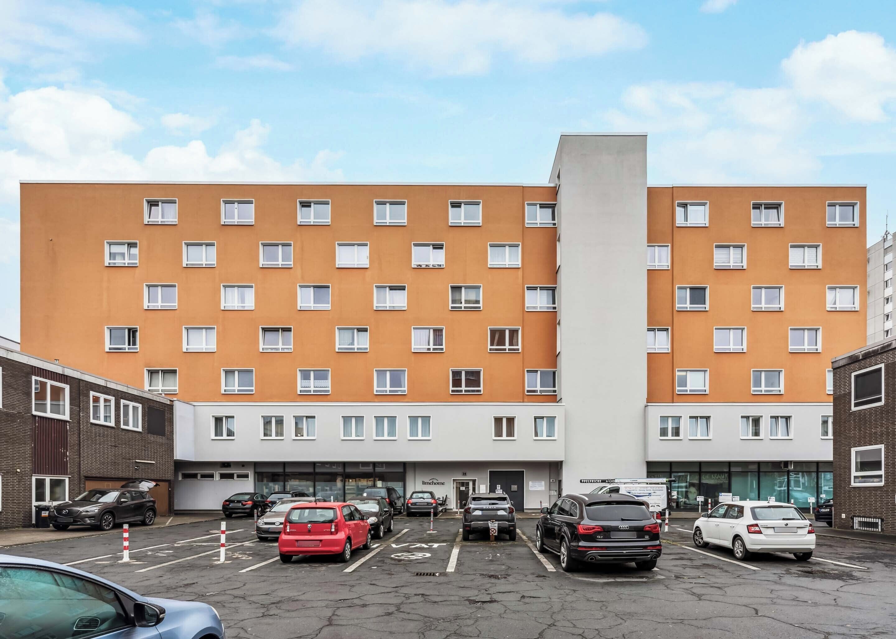 A multi-story hotel with a central tower, parking lot, and various vehicles.
